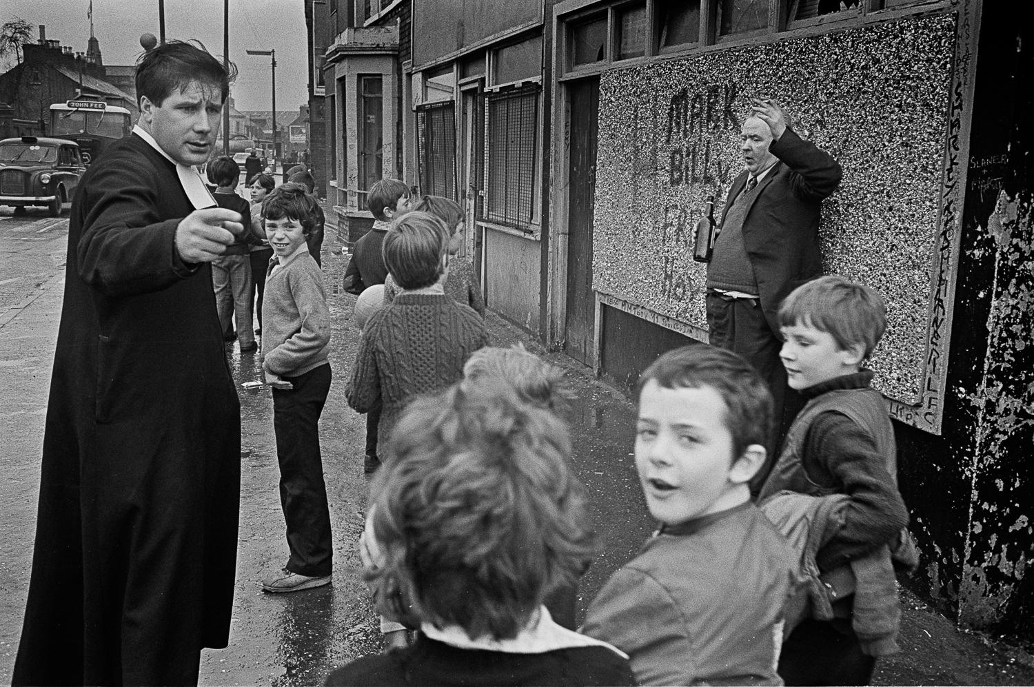 Een groep schoolkinderen in Belfast loopt in 1980 met de priester langs een dronken man.