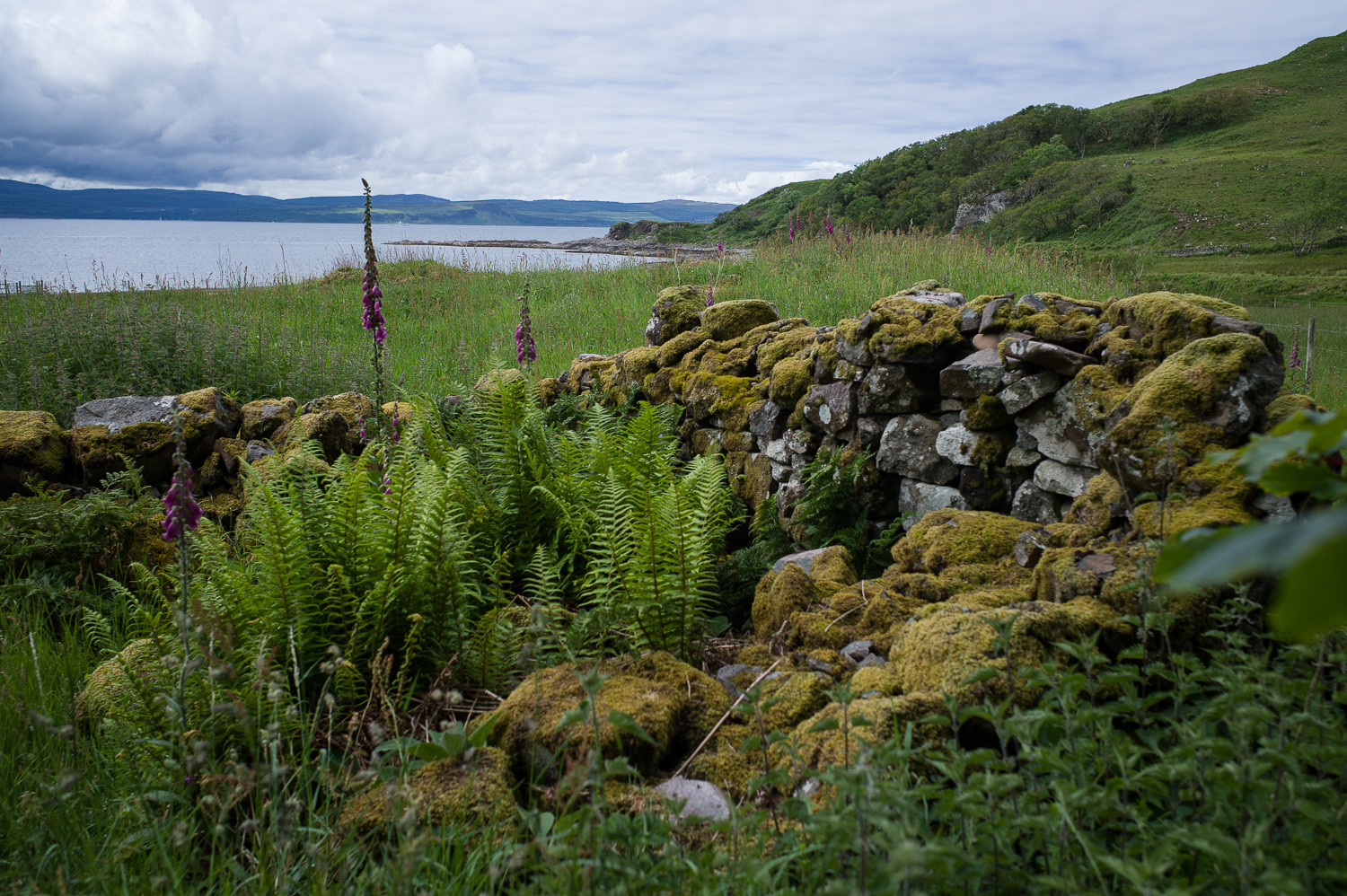 resten van de muren van een huis, de zee in de verte.