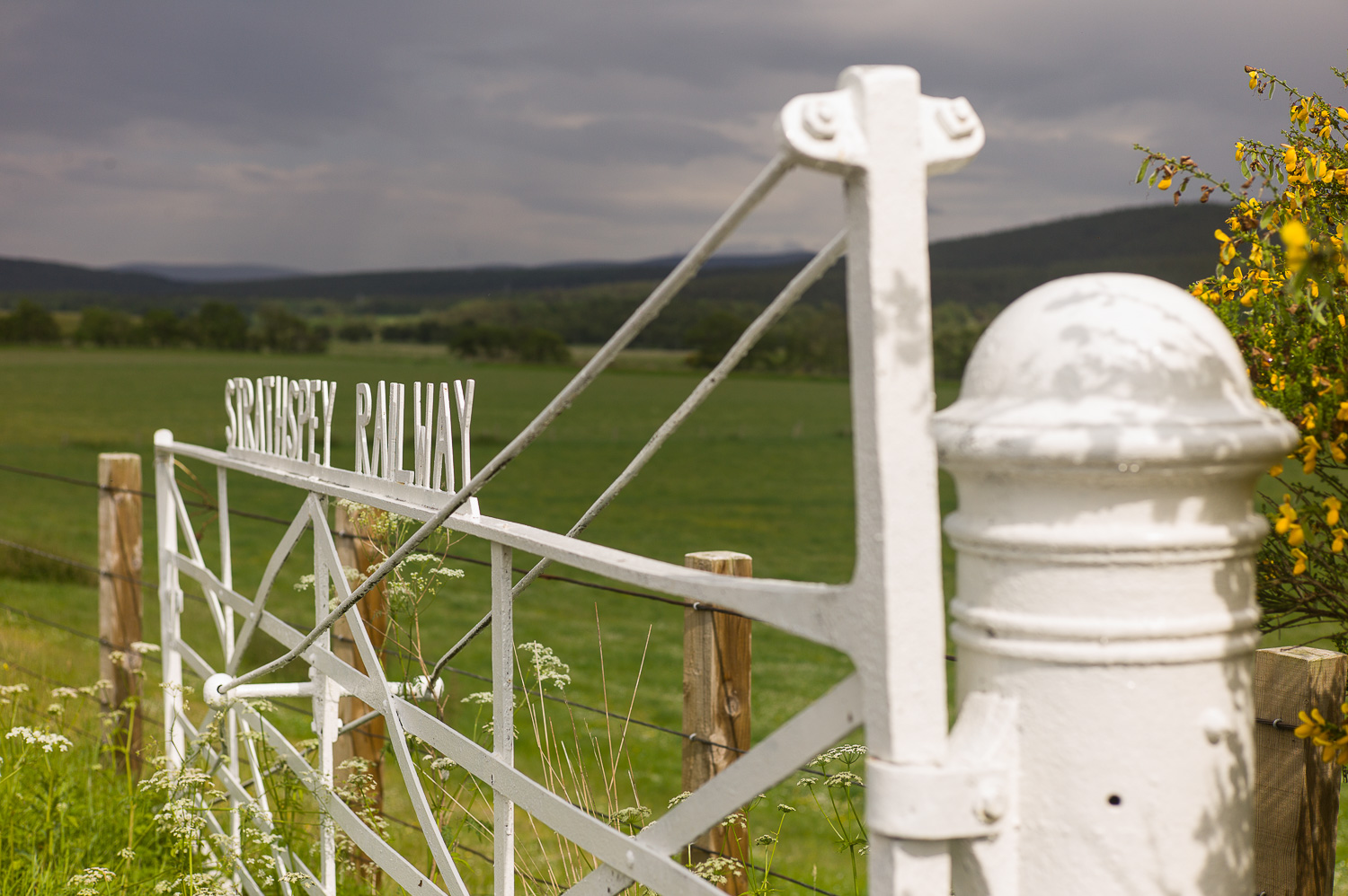 Een wit ijzeren hek met Strathpey Railway in ijzeren letters er op.